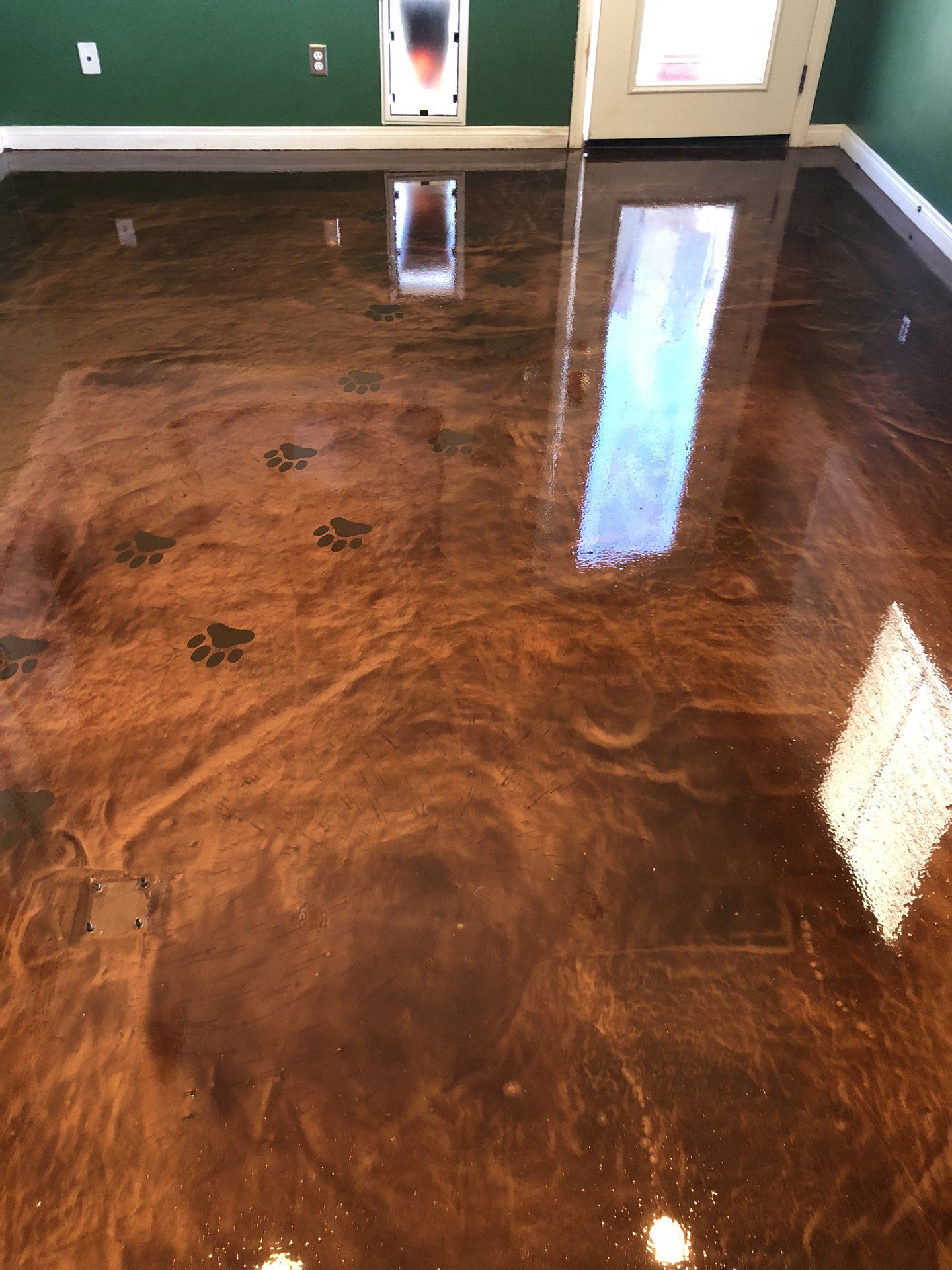 Copper metallic epoxy floor with paw print accents in a room with green walls