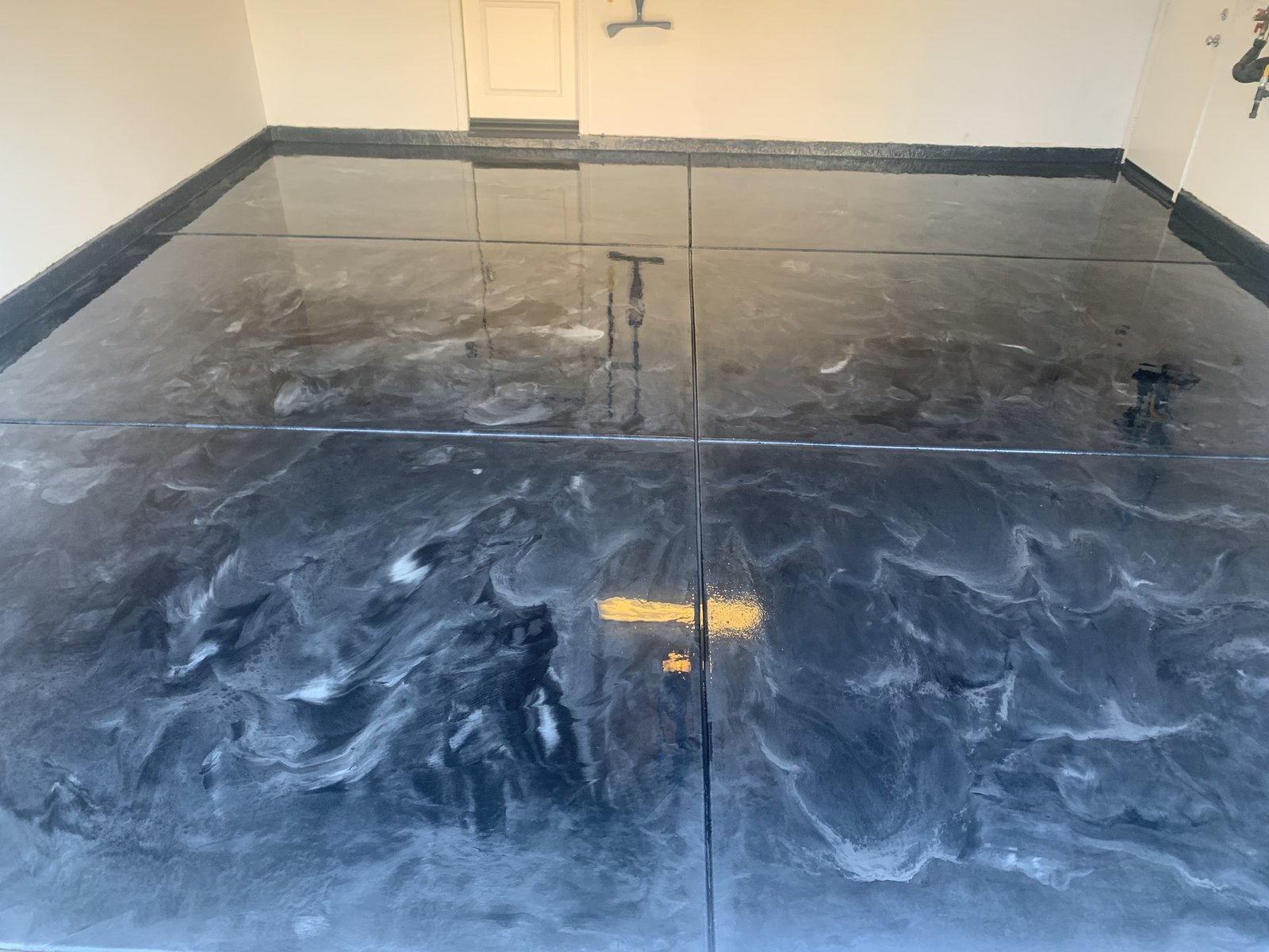 Gray and blue metallic epoxy garage floor with marbled swirl pattern and dark cove border