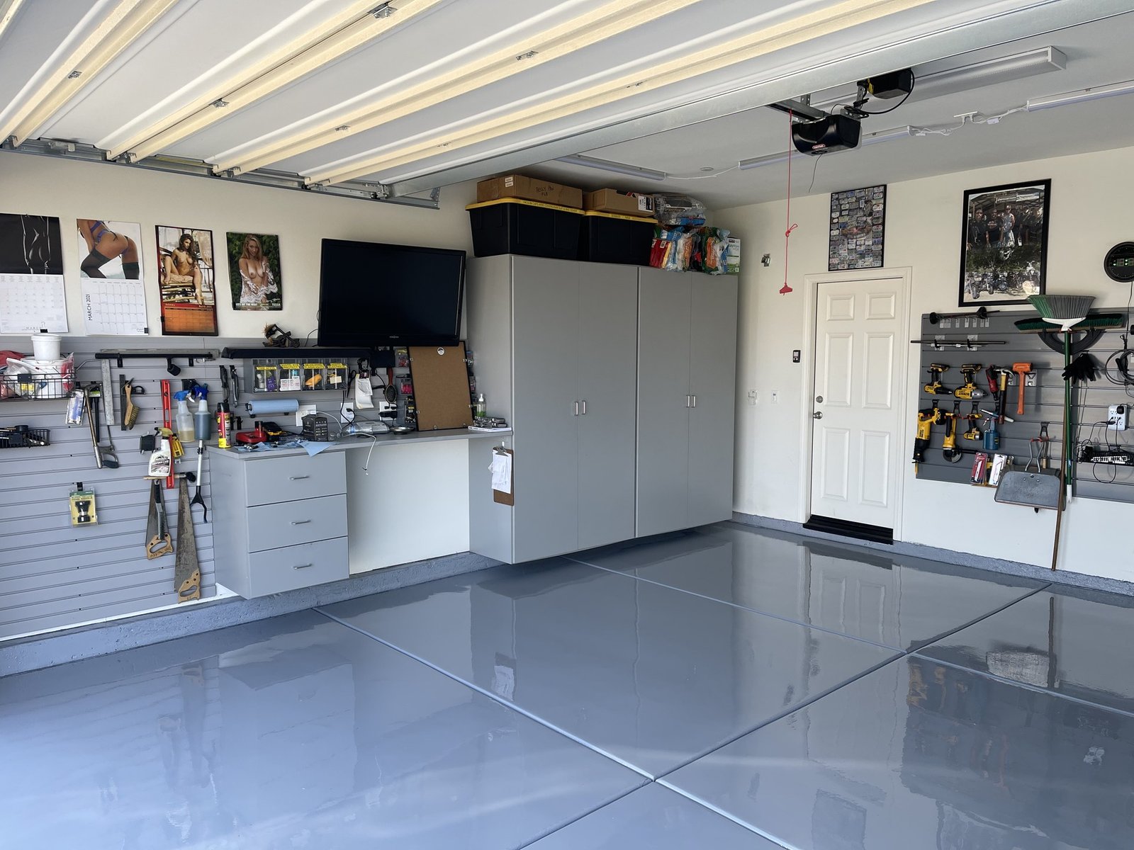 Solid gray epoxy garage floor with slatwall storage and gray cabinets